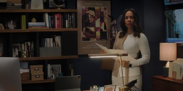 woman holding papers in a modern office setting with bookshelves and a lamp