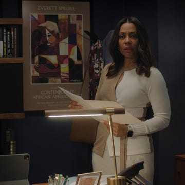 Working from home woman holding papers in a modern office setting with bookshelves and a lamp
