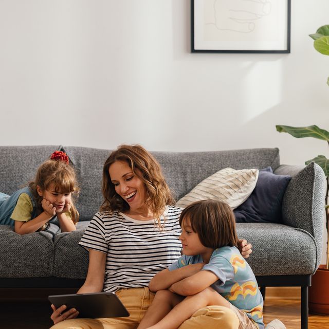 happy family moments: the mother sits on the floor and watches something on the digital tablet with her kids