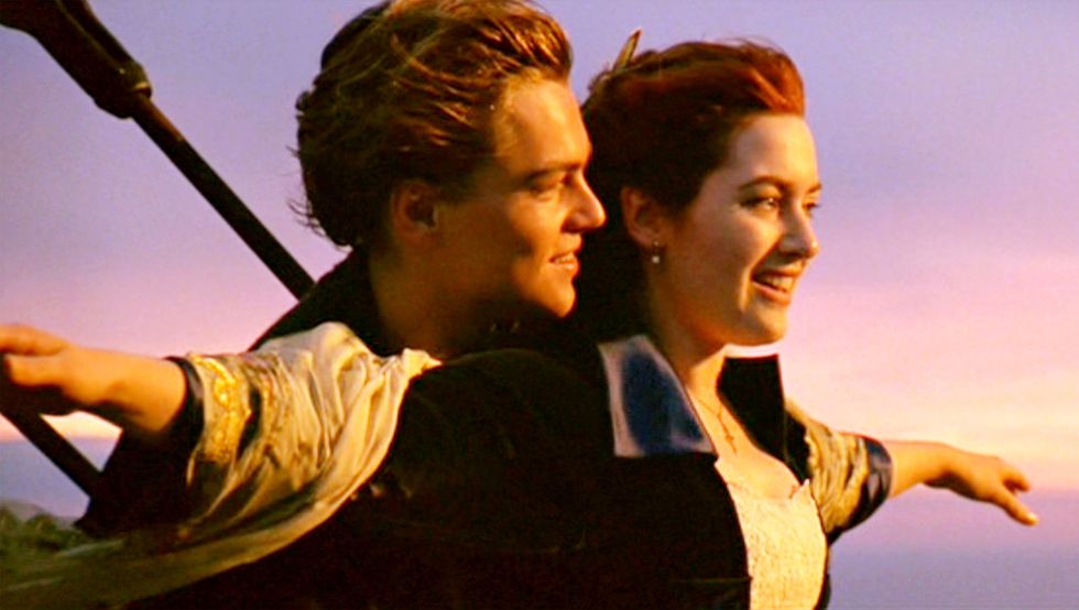 leonardo dicaprio holding kate winslet, who has her arms expanded outward, on the front of a ship in a promotional still for the movie titanic