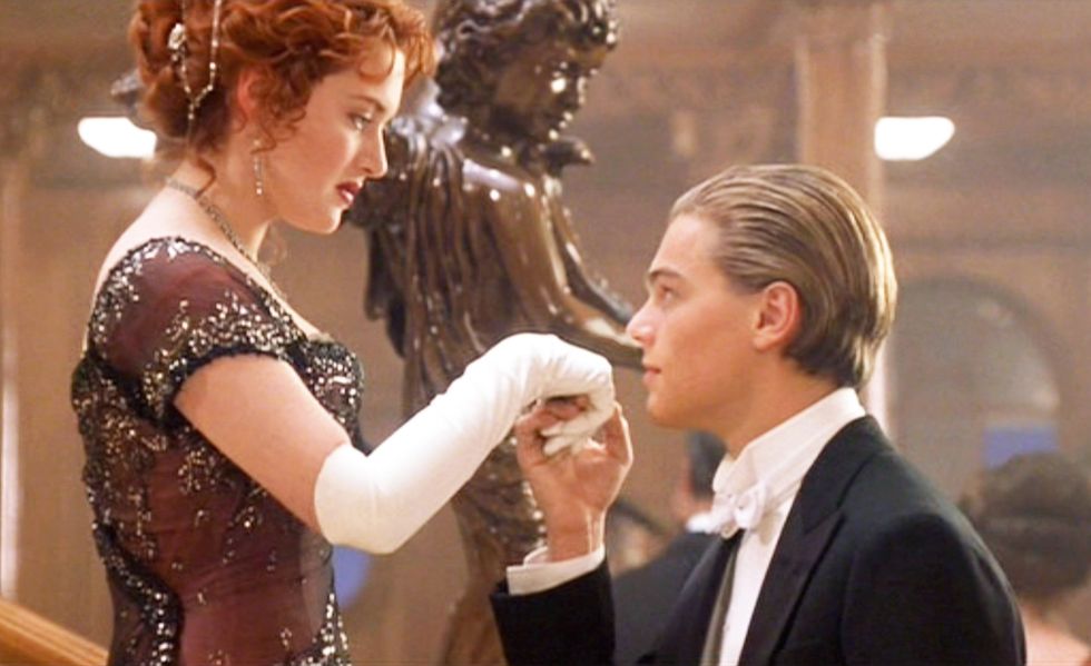 kate winslet and leonardo dicaprio in a scene from ﻿the film titanic﻿, with dicaprio holding winslet's hand on a set of stairs, both of them in fancy attire