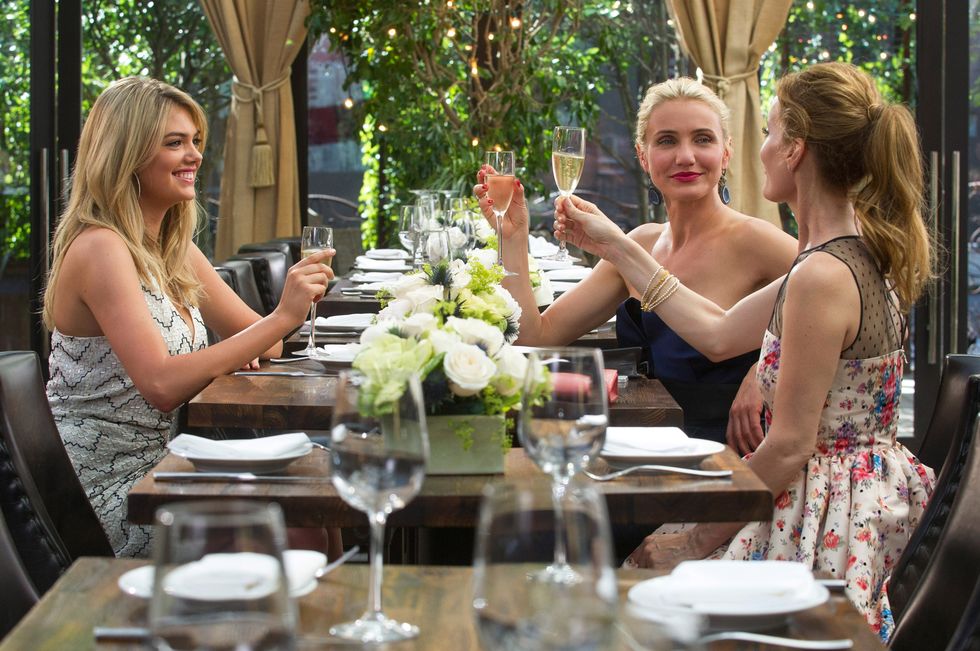 kate upton, cameron diaz, and leslie mann drink sparkling wine at a table in the movie in the other woman