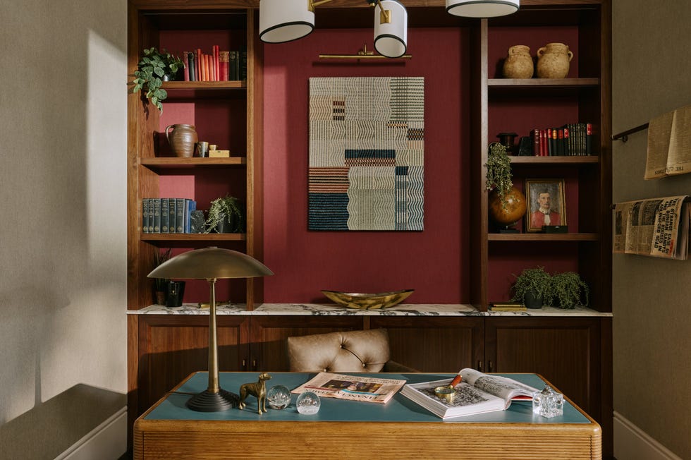 a desk chair and shelving in a study painted in deep red