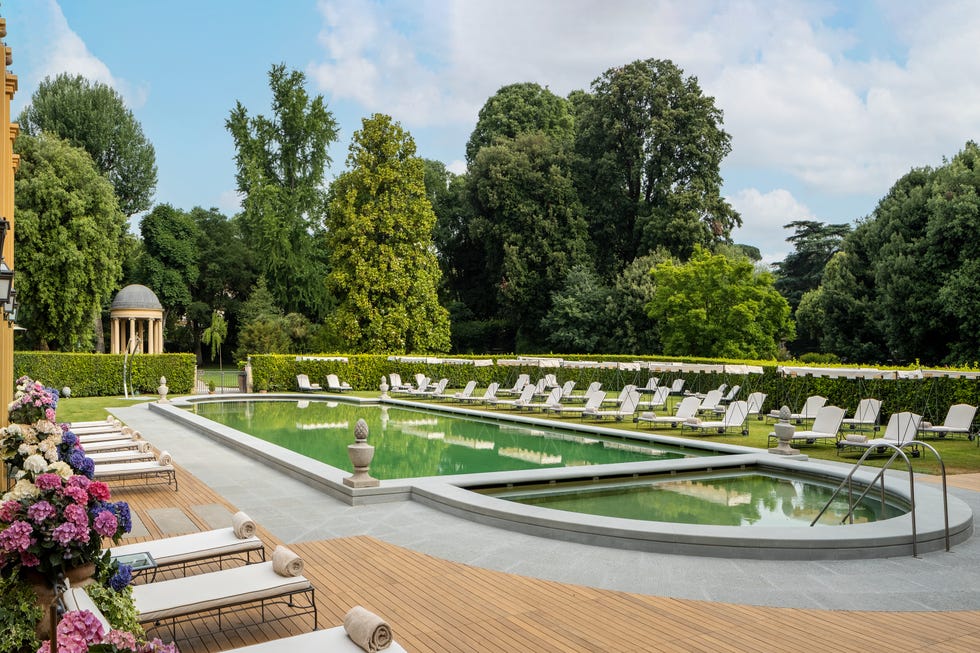 four seasons hotel firenze outdoor pool with surrounding white loungers, hydrangeas, trimmed hedges, and other greenery