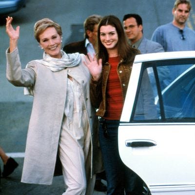 a woman waving near a car with a group of people in the background