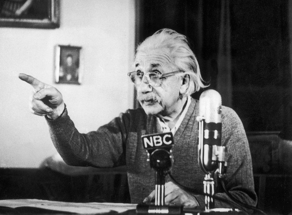 Albert Einstein señala mientras da un discurso frente a los micrófonos de la televisión.