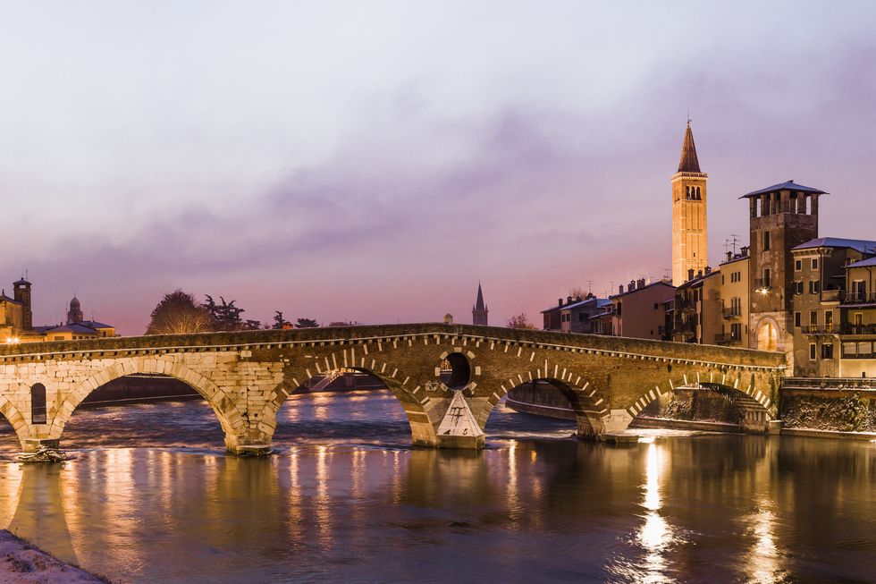 the river adige and the ponte bridge di pietra, on the background the bell tower of the chiesa church di santa anastasia