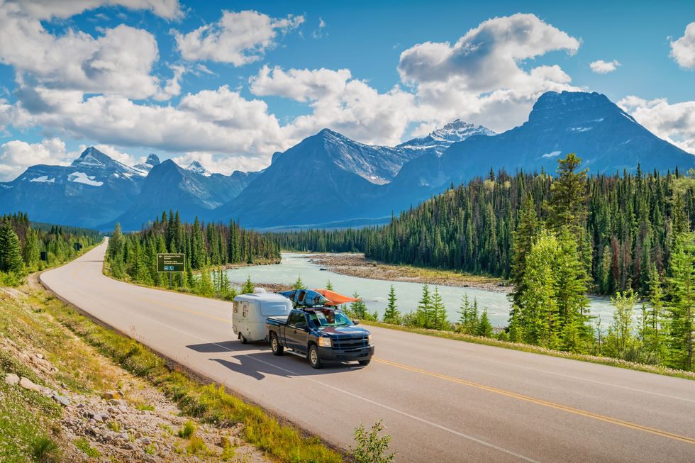 pick up truck with travel trailer and kayaks drives on the icefields parkway in jasper national park, canadian rockies