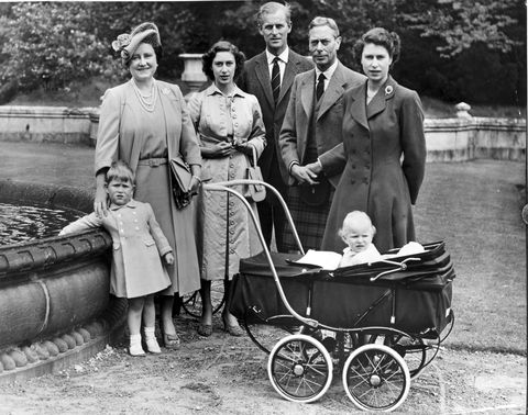prince charles, elizabeth the queen mother, princess margaret, prince philip, king george vi, princess elizabeth, and princess anne pose for a photo next to a fountain outside