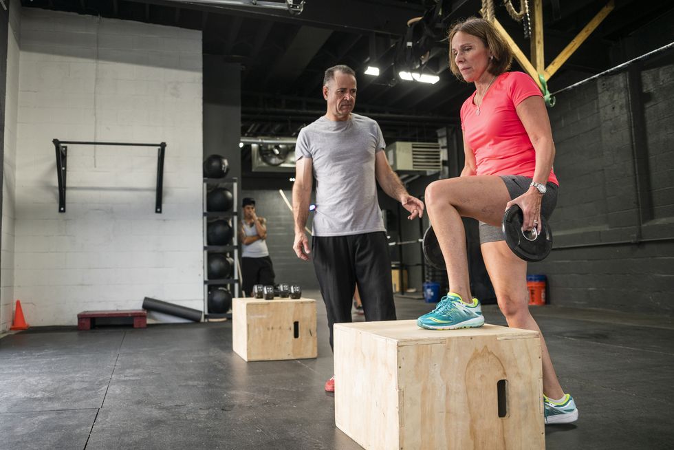 the senior 55 years old latino woman doing step up with weight exercise in the gym