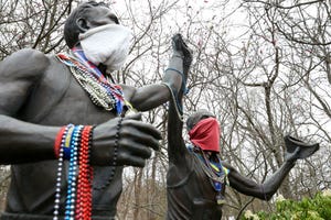 una estatua que honra al maratón de boston con sus dos figuras de corredores con mascarilla y medallas tras la suspensión de la prueba