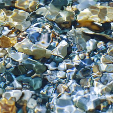 the sun shone through the stream on the pebbles