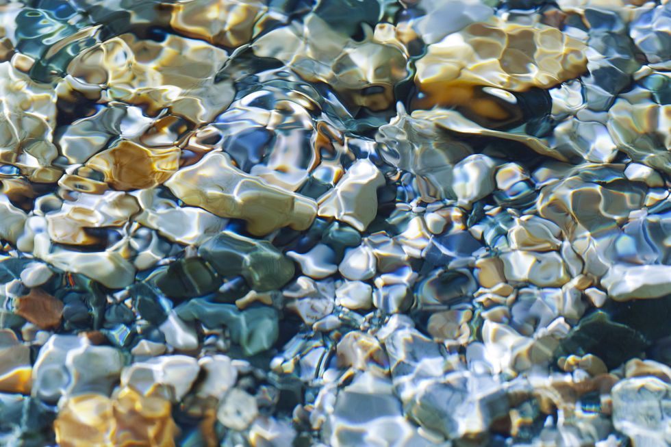 the sun shone through the stream on the pebbles