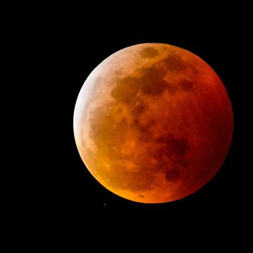 a blood moon, or full moon with a reddish shadow due to a total lunar eclipse, in the night sky