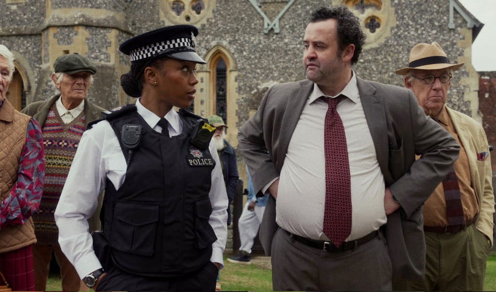 group of people including a police officer and a man in a suit in a public setting