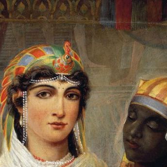 cleopatra vii wears a colorful head piece, pearl jewelry and a white scarf with a floral bouquet in front of her chest