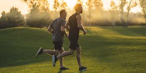 the two sportsmen running on the grass in the park on the sunny background