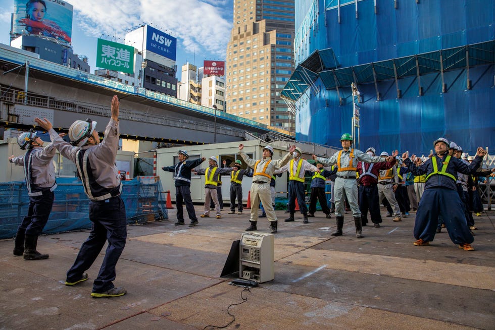 Deze bouwvakkers beginnen elke dag met ochtendgymnastiek in een bouwput in Shibuya Tokio heeft een tekort aan servicemedewerkers en arbeiders Japan versoepelde vorig jaar zijn strenge immigratiebeleid om buitenlandse werknemers aan te kunnen trekken