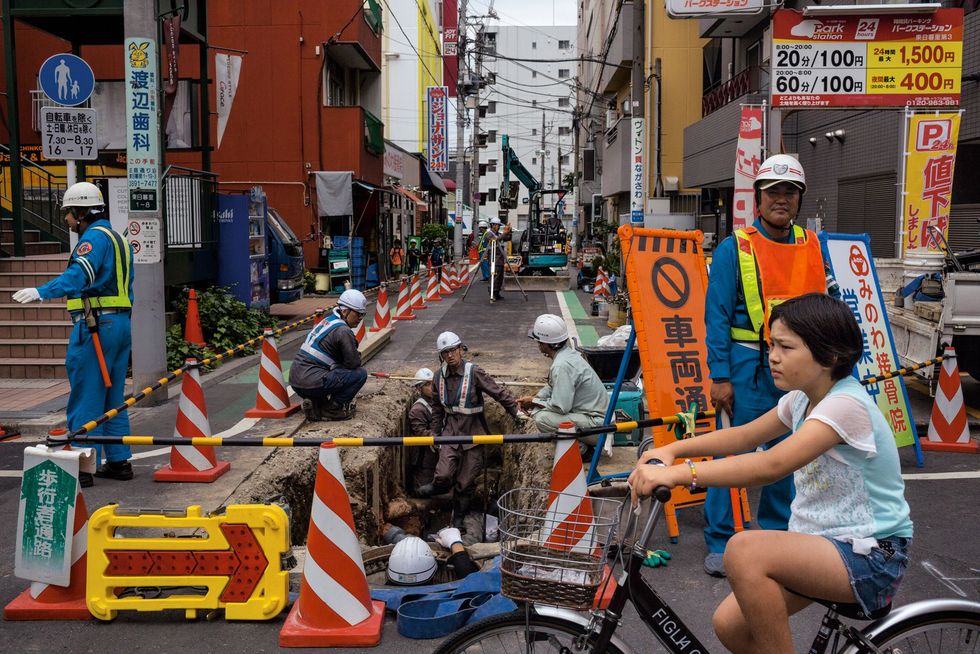 Vorige eeuw werd Tokio tweemaal herbouwd na de Kantoaardbeving in 1923 en na WO II De stad is nu een schoolvoorbeeld van efficinte organisatie Hier leiden beveiligers voetgangers en fietsers beleefd om werkzaamheden in de wijk Minowa heen