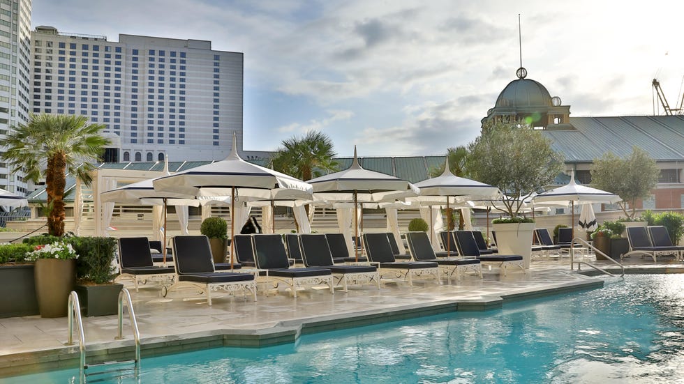 a pool with lounge chairs and umbrellas by a building