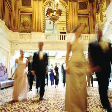 theater goers in formal attire, walking through lobby, blurred motion