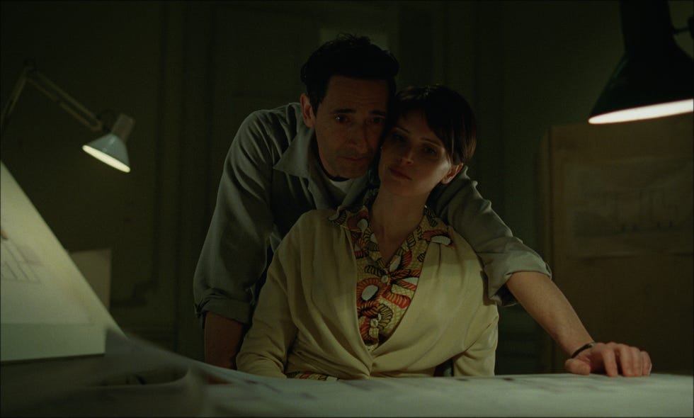 two individuals in a dimly lit room engaged in close proximity focused on a layout