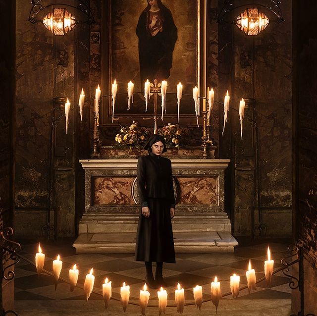 a person standing in front of a statue with candles on it