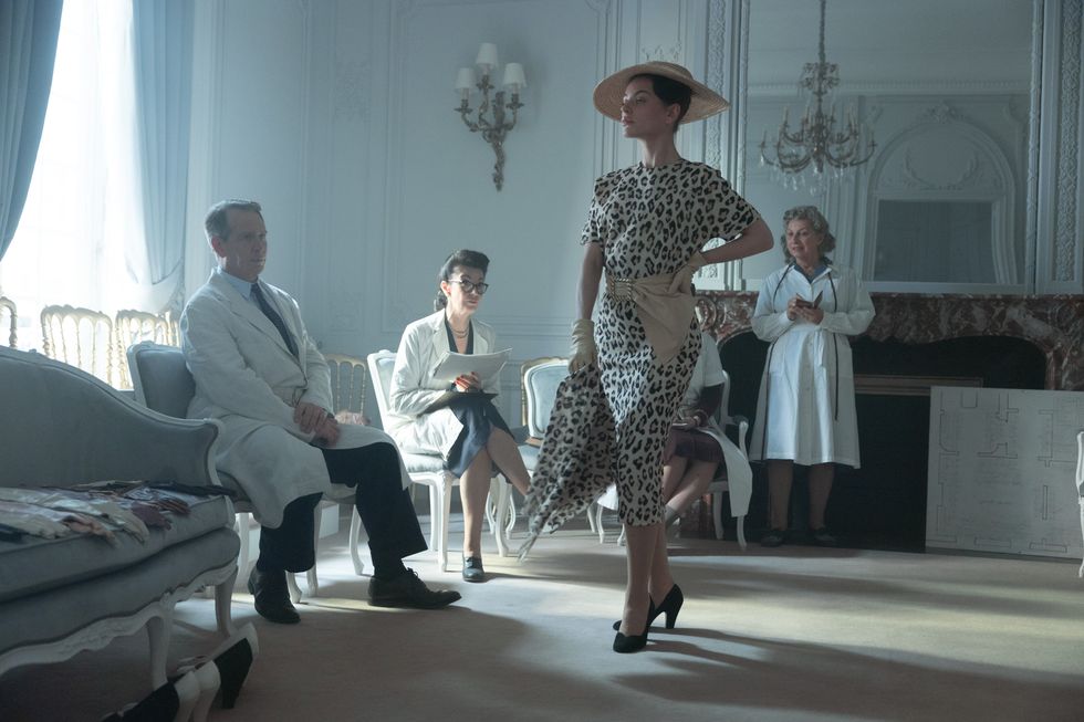 a person in a dress dancing with a group of men in a room