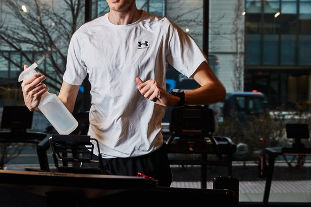 a person running on a treadmill sprays a spray bottle of water at his face