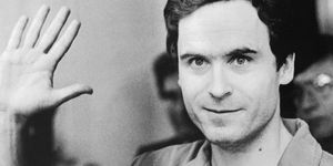 ted bundy waves and looks directly at the camera, he is wearing a collared shirt in the black and white photo