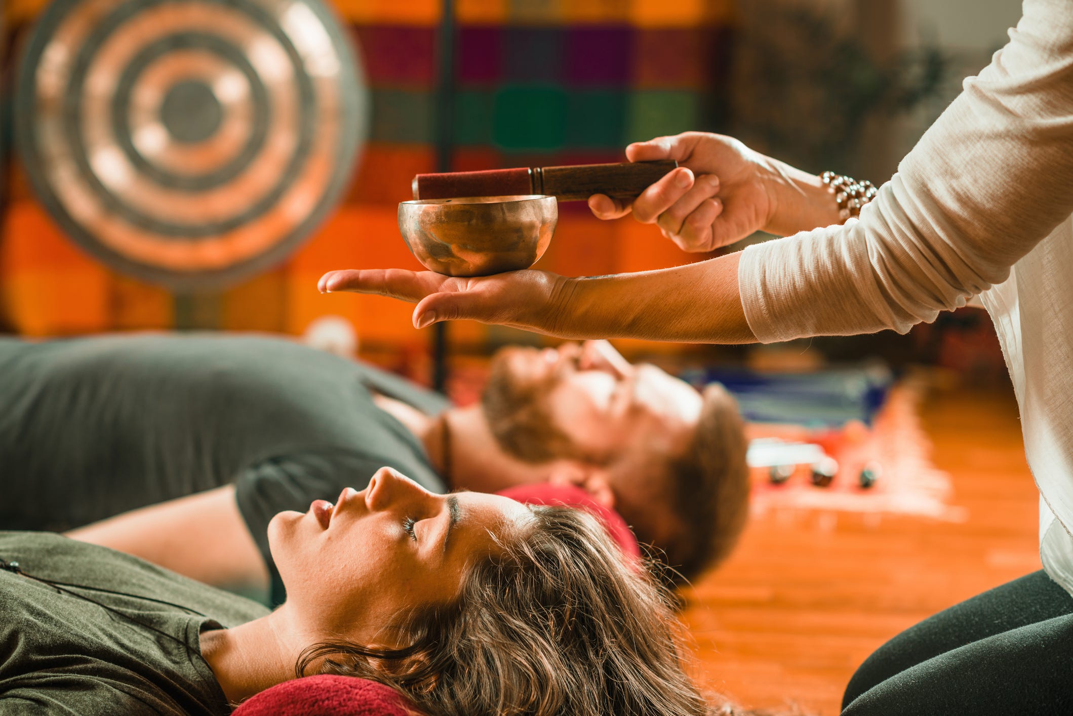 therapist playing rin gong over couple while performing music therapy at spa