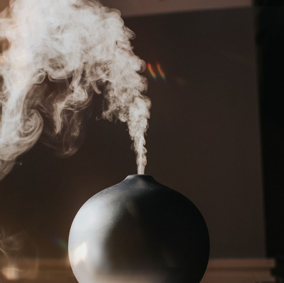 a thick mist gently rises and falls from an oil diffuser in a home environment
