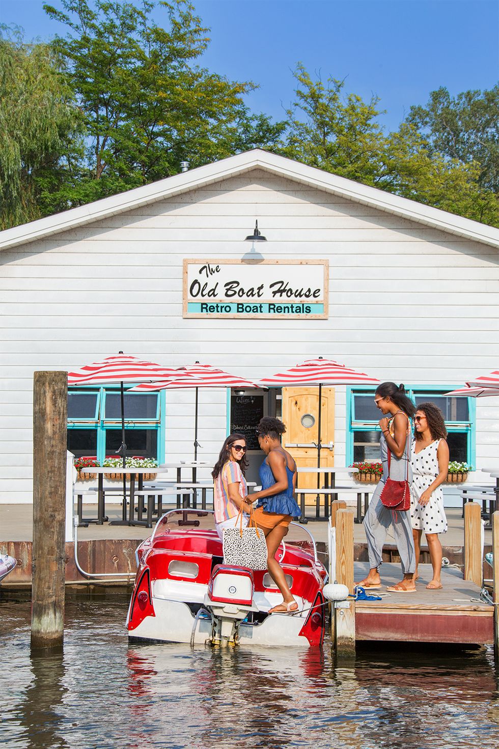 group of women boarding a red vintage speedboat at the dock of retro boat rentals in saugatuck michigan