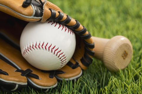 ball inside catchers mitt and bat on grass