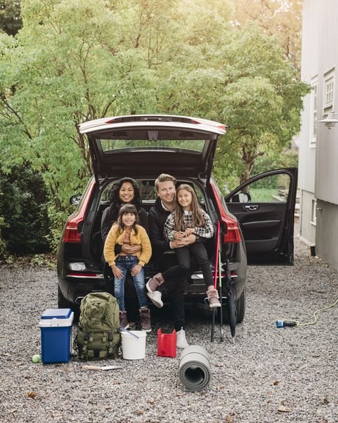 smiling parents sitting with daughters in trunk of electric car