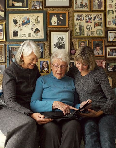 three older women looking at a family photo album