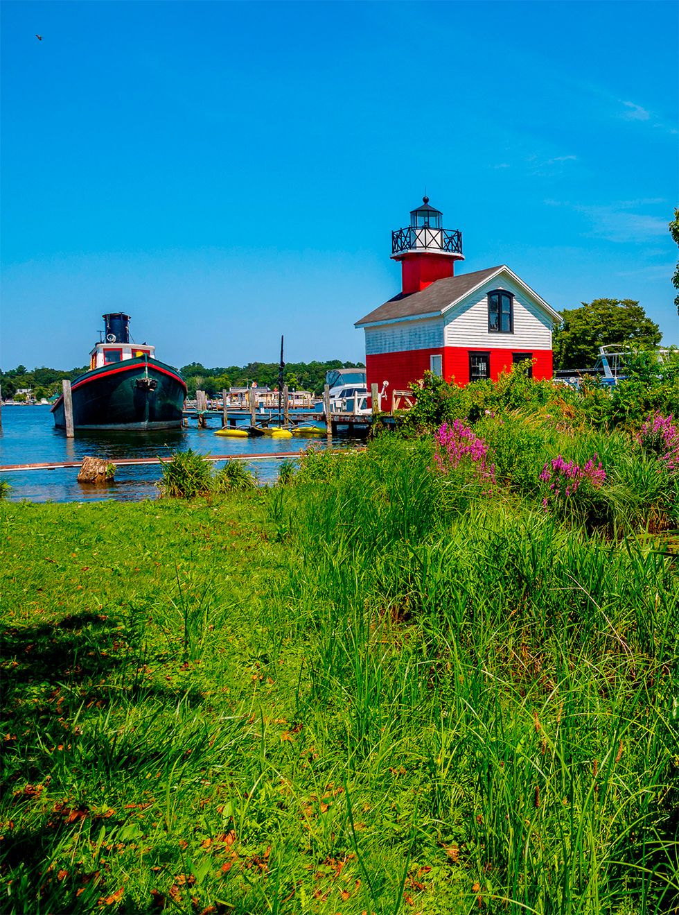 red lighthouse next to black tugboat in saugatuck michigan