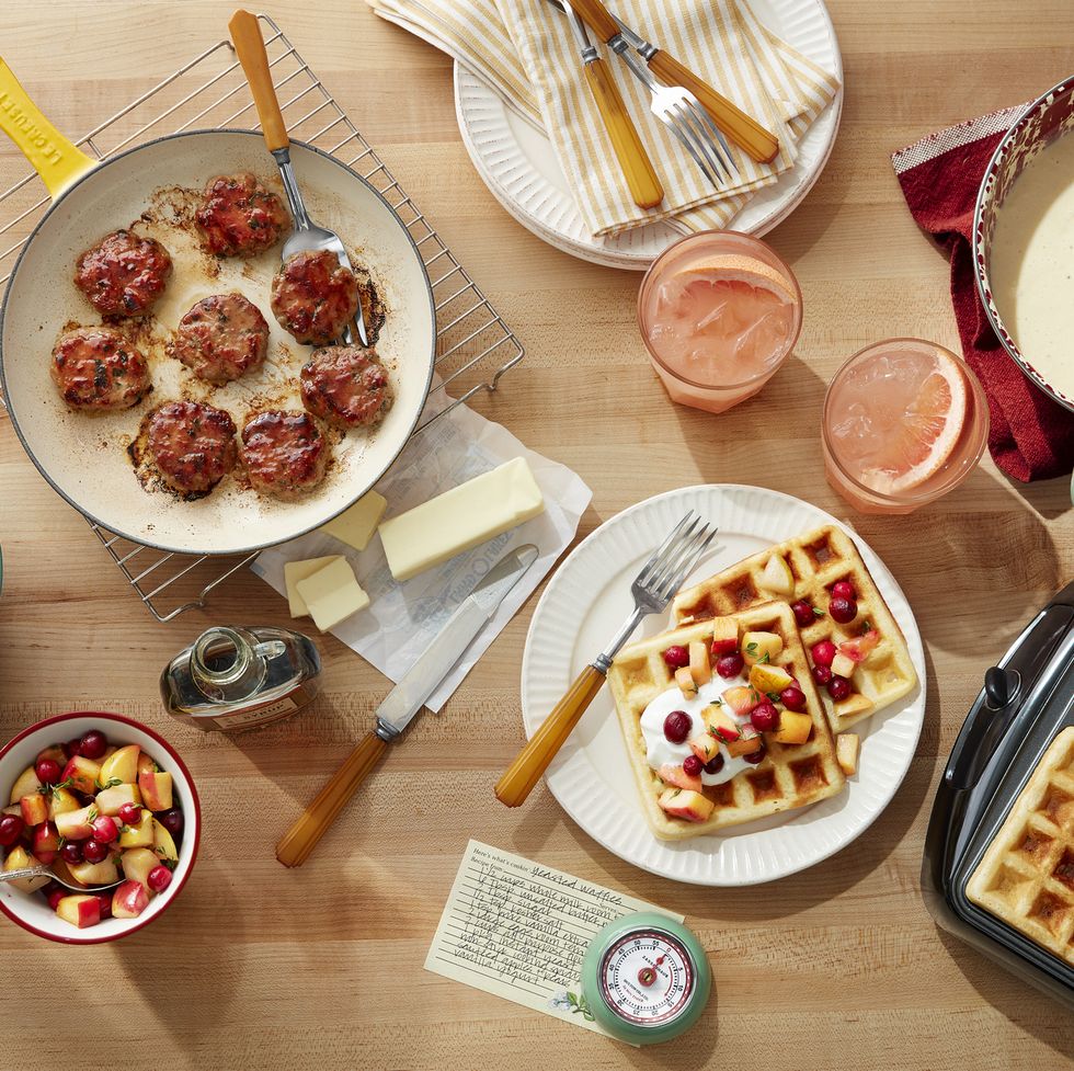 a table with sausage and waffles and grapefruit drinks