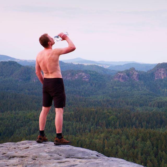 thirsty hiker in pants with bottle of water sweaty tourist