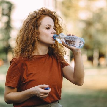 thirsty young redhead woman drinking water