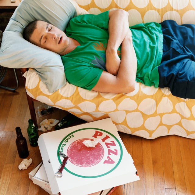 thirty something man lying asleep on a sofa in an apartment