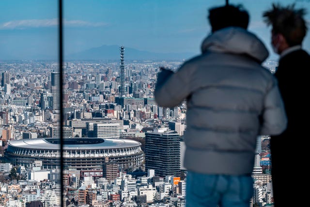 dos japoneses señalan el estadio olímpico de tokio, donde se celebrarán los juegos olímpicos en julio de 2021 si la pandemia del covid 19 lo permite