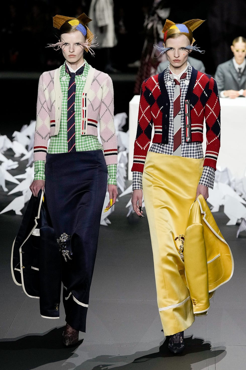 Two models displaying colorful and patterned outfits during a fashion show