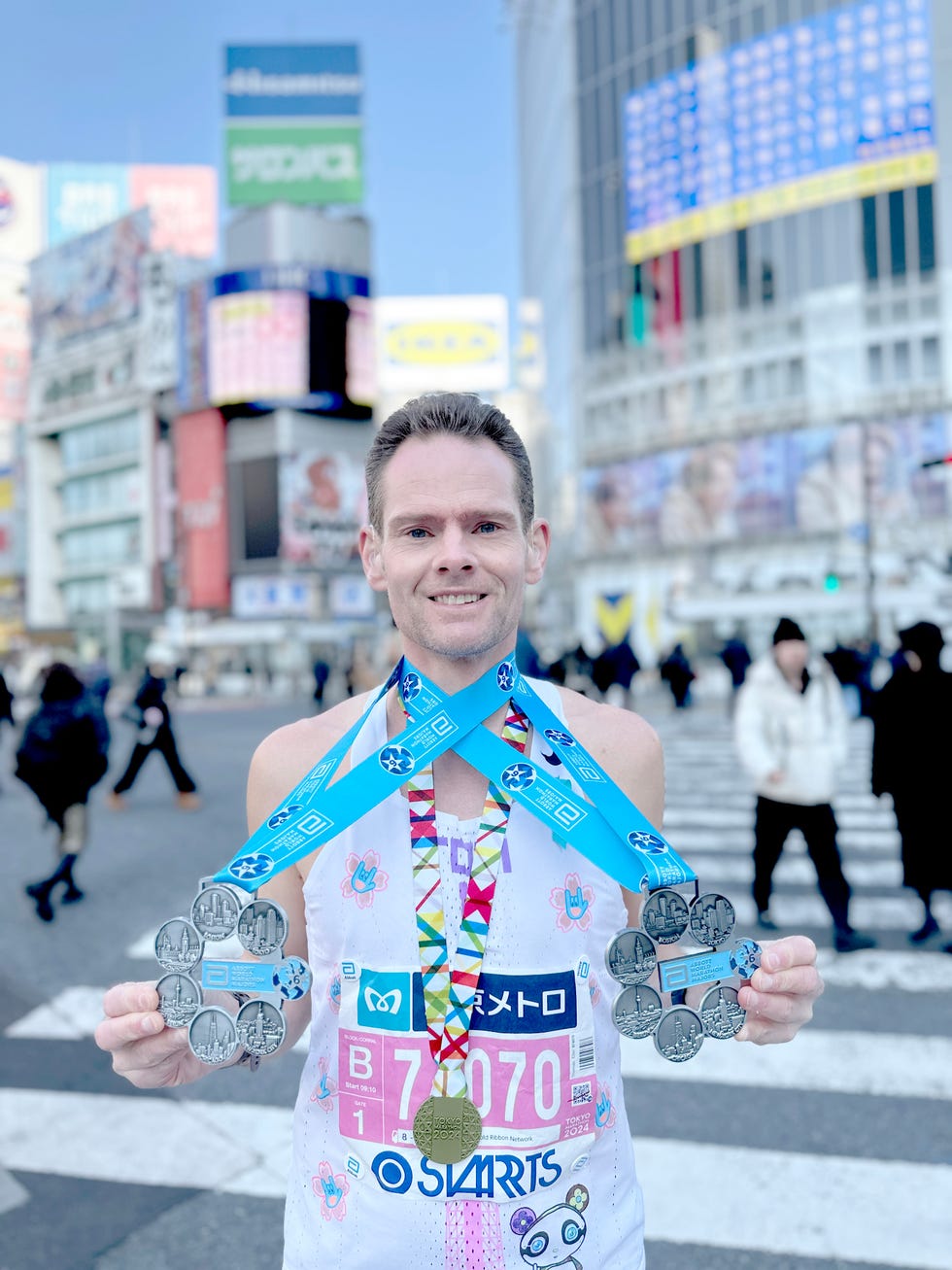 runner displaying multiple medals in a busy urban area