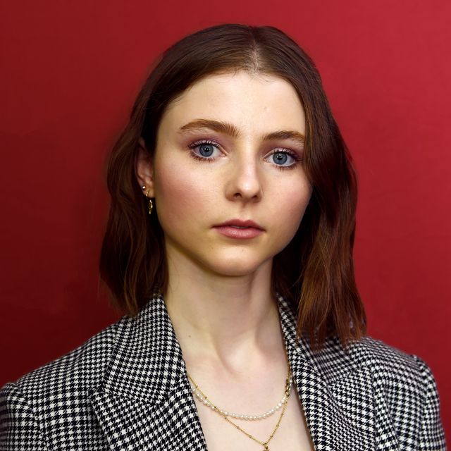 actress thomasin mckenzie stands in front of a red backdrop