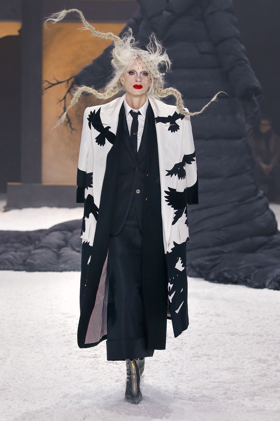 a person in a black coat and red lipstick with a white and black scarf on the head