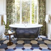 graphic flooring tile in the primary bath with a burnished cast iron tub in front of a window