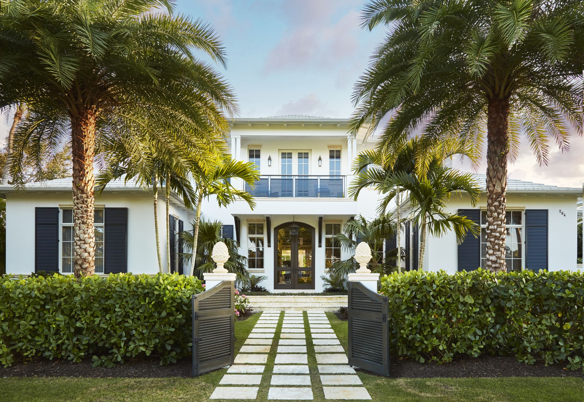a grid of coral stone pavers creates a tidy path into 
a u shaped entry court yard and allée of palms