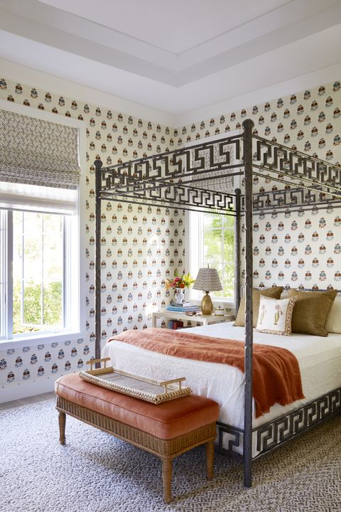 a guest room has a hammered metal bed and patterned wallpaper