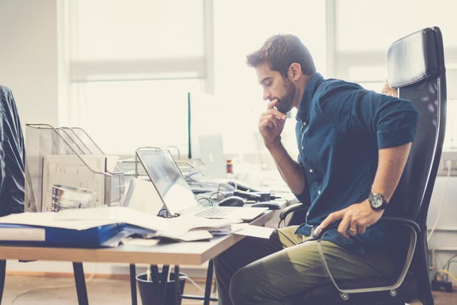 Thoughtful businessman looking at laptop in office